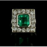 Vintage emerald and diamond cluster ring, central emerald cut 3.19 carats, set in a rectangular