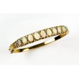 Gold hinged bangle set with opals and diamonds, in scroll mount with daisies on the sides . Opals