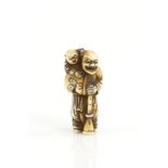 An ivory netsuke of a Dutchman, or other Gaijin, holding a long horn and carrying a child, signed