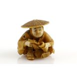 A stained ivory netsuke of a man, wearing a jingasa and holding a pipe with his right hand, signed