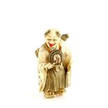 An amusing ivory netsuke of Oni Nembutsu with an articulated head, wearing geta, and carrying his