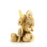 A stained ivory okimono, carved as a seated street vendor slicing a fruit, signed Kogetsu, 9 cm