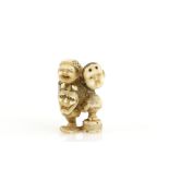A stained ivory netsuke of a standing mask vendor, 20th CenturyProvenance: The Property of a Lady.