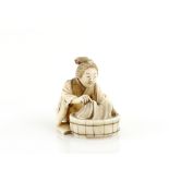 A stained ivory netsuke of a women beside a circular washing tub; signed on the base with two kanji,