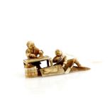 A small ivory okimono, or small netsuke with single himotoshi; carved as two men preparing food,