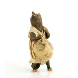 A stained ivory okimono of a standing badger, beating a large mokugyo with a single stick, 9 cm