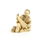 A stained, sectional ivory okimono of an umbrella and parasol maker, 9 cm high, Meiji