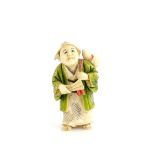 A Yasuaki (Homei) School, coloured ivory netsuke of a standing man, wearing a green kimono and