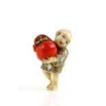 A Yasuaki (Homei) School coloured ivory netsuke of a boy, carrying a large red Daruma Doll, signed