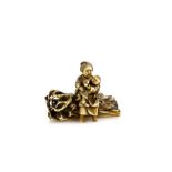 A small stained ivory netsuke or okimono of a mother, seated on a log with her child; two kanji on