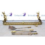 Brass fender with cast scroll decoration, 132cm wide, together with fire irons..