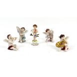 Continental porcelain figures of cherubs with musical instruments, one holding a flaming heart,