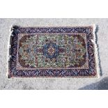 Persian green ground silk rug with a main blue border the centre with repeating foliate forms and