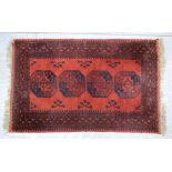 Afghan red ground rug with multiple borders the centre with four medallions, 118cm x 113cm .