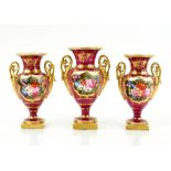 Set of three porcelain burgundy ground twin handled vases the centre cartouche painted with flowers,