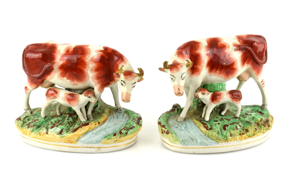 A pair of 19th century Staffordshire models of cows and calves, each 23 cm wide.