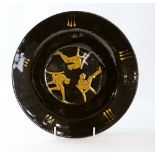 A Prue Cooper studio pottery slipware dish covered in a dark brown glaze, the centre decorated in