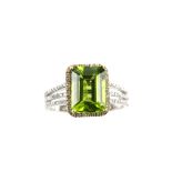 Modern diamond and peridot set dress ring, the central peridot 3.70 carats, diamond border and