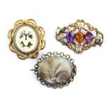Three brooches, one hairwork, another set with an amethyst, orange and purple paste stones, and a
