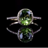 Peridot and diamond dress ring, oval cut peridot, 8.9 x 7 mm, set in diamond boarder with diamond