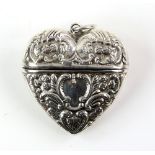 Heart form silver pendant case with embossed decoration .