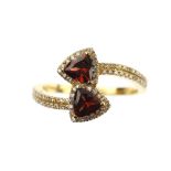 Diamond and garnet ring set with two deep red trilliant cut stones within a diamond set mount, 18 ct