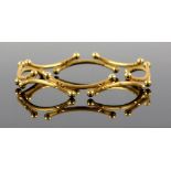 Gold bangle, made up of a series of curved sections with spherical terminations, brushed finish,