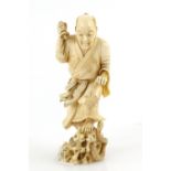 A stained ivory okimono, carved as a standing man killing a snake with a ko-wakizashi, 13 cm high,