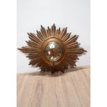 A GILT SUNBURST FRAMED MECHANICAL CLOCK WITH KEY