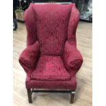 A RED UPHOLSTERED ANTIQUE WING BACK ARM CHAIR