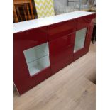 A RED LACQUERED UNIT WITH 2 GLAZED DOORS AND 4 DRAWERS