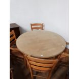 A LARGE CIRCULAR GLASS TOPPED BEECH TABLE WITH 4 MATCHING RUSH SEATED ARM CHAIRS