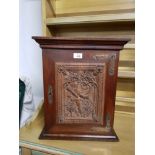 A HANGING CABINET WITH CARVED FRONT PANEL WITH WOODSMAN AND INTERIOR PIGEON HOLES