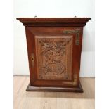 A HANGING CABINET WITH CARVED FRONT PANEL WITH WOODSMAN AND INTERIOR PIGEON HOLES