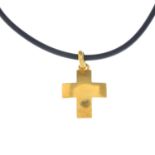 A pendant. Designed as a domed cross, with loop surmount, suspended from a black rubber cord.