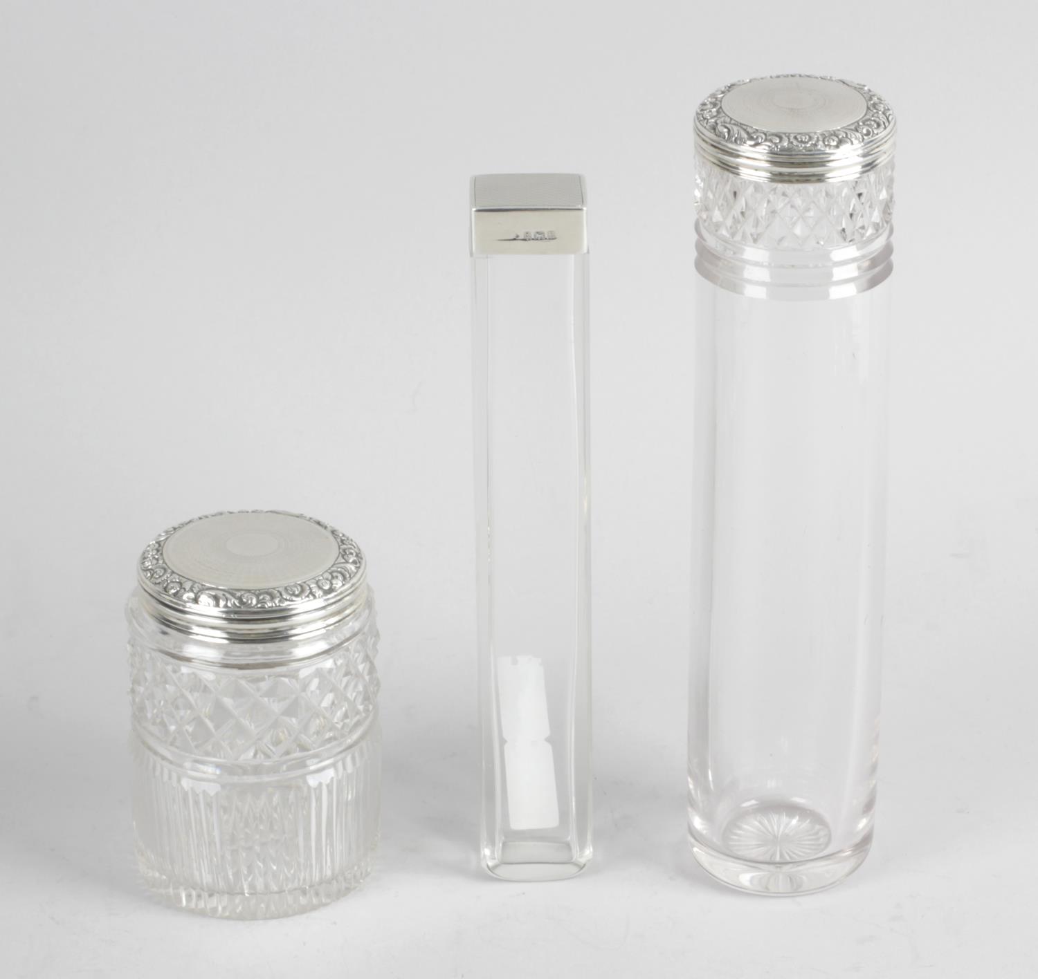 A clear glass vanity jar of long cylindrical form with diamond cut band and a smaller,