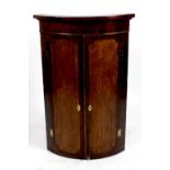 A 19th century oak and mahogany crossbanded wall hanging corner cupboard of bow fronted form,