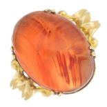 An agate ring. The oval agate cabochon, to the stylised foliate shoulders and tapered band.