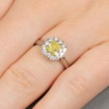 A platinum cushion-shape Fancy Intense Yellow diamond and brilliant-cut diamond cluster ring.With