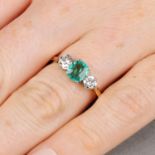 An emerald and brilliant-cut diamond three-stone ring.