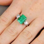 An emerald and brilliant-cut diamond three-stone ring.