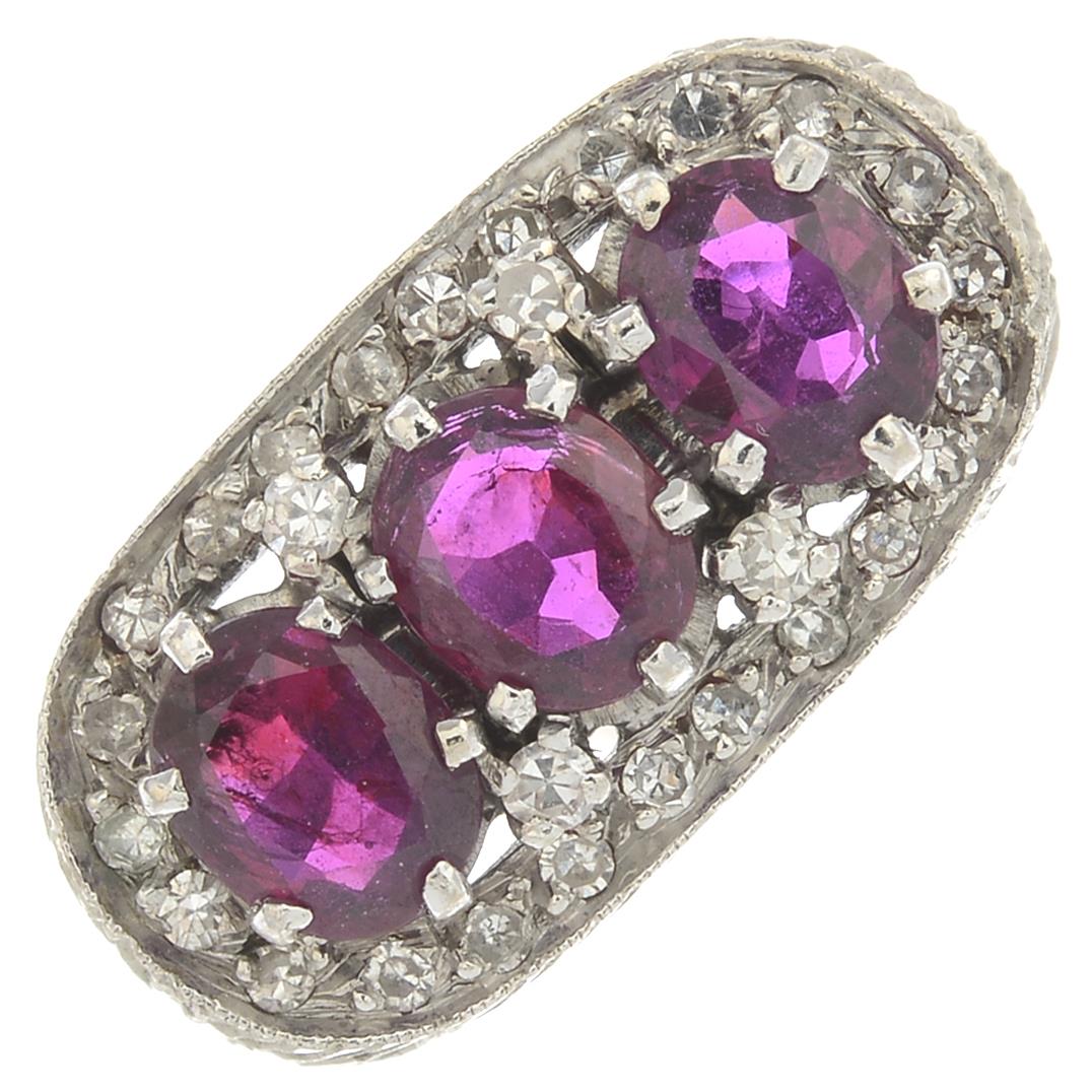 A mid 20th century gold ruby three-stone and diamond cluster ring.Estimated total diamond weight