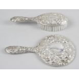 A modern silver mounted hand mirror with embossed scrolling foliate and satyr decoration,