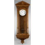 A late 19th century oak and stained wooden cased Vienna style wall clock,