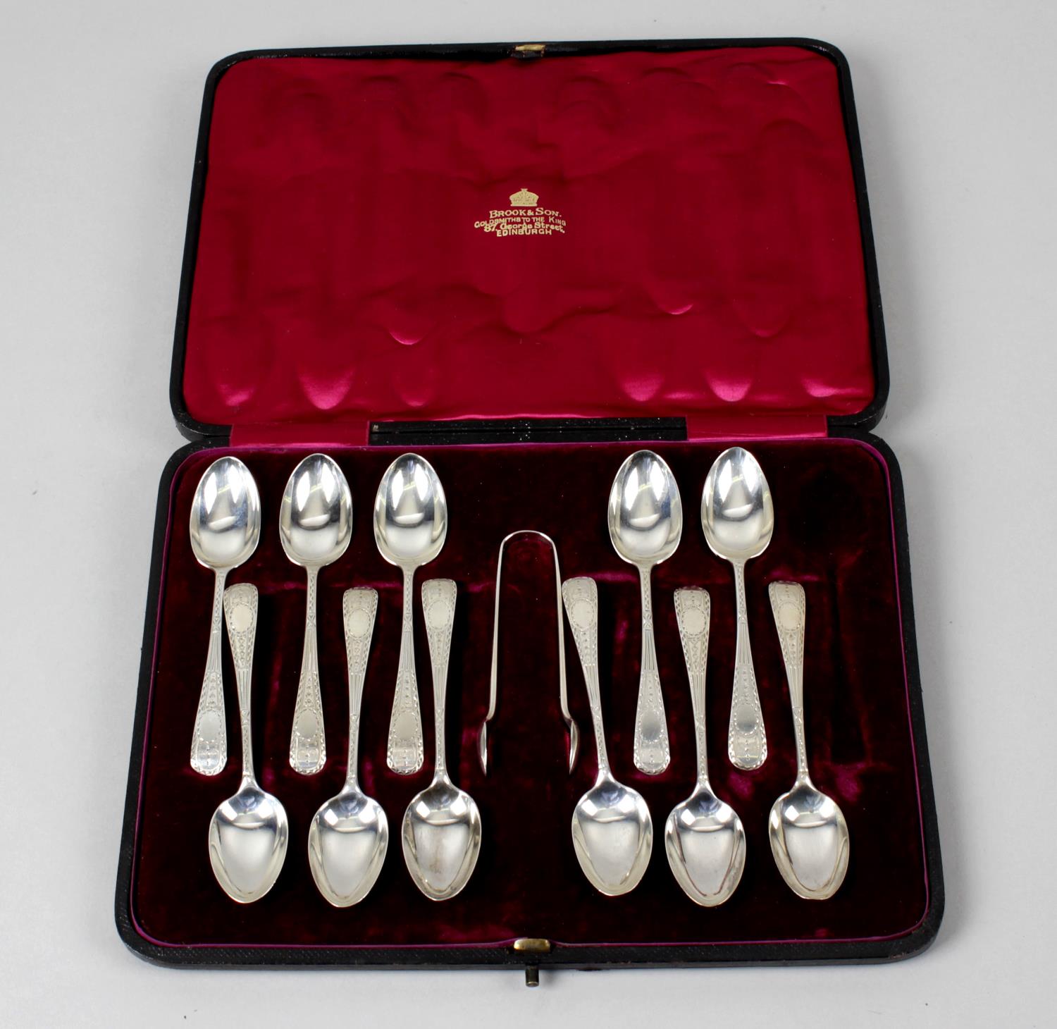 A turn of the century cased set of eleven teaspoons and a matched pair of sugar tongs,