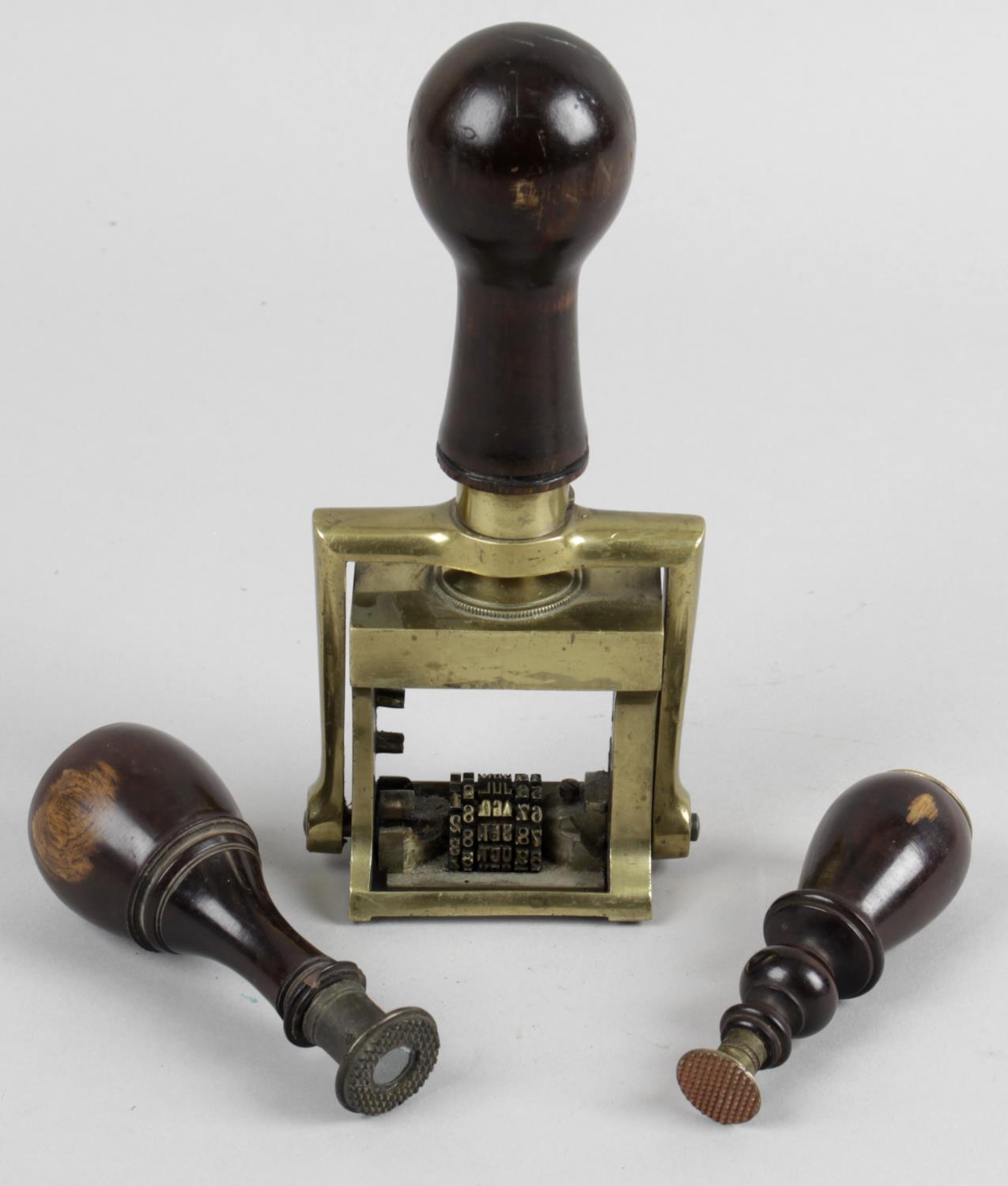 A late 19th century brass bodied mechanical Day and Date desk stamp with fitted stained wooden
