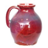 A Ruskin Pottery high fired single handled vase decorated in an all over red and purple flambe