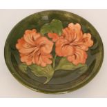 A Moorcroft Hibiscus pattern shallow circular side plate decorated with tube lined flowers and