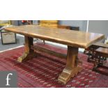 A 17th Century style oak refectory dining table on trestle end supports united by a rail stretcher,