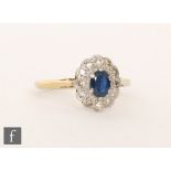 An 18ct sapphire and diamond cluster ring, central sapphire within a twelve stone diamond surround,